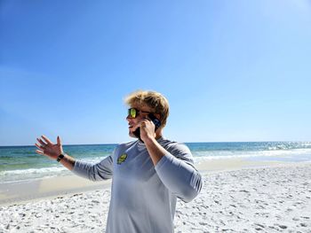 Agitated millennial on cellphone at beach upset.