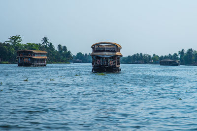 Boat in sea by building against clear sky