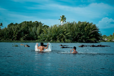 People swimming in pool against sky