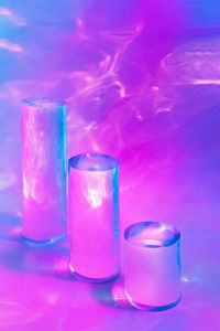 Three clear glass cylinder podiums on pastel pink background