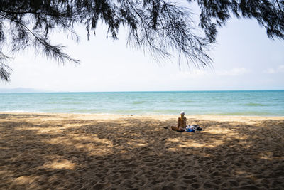 People sitting on beach by sea against sky