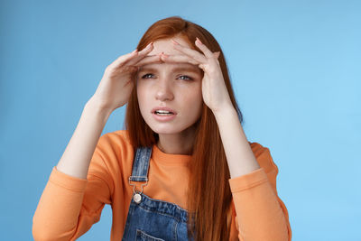 Portrait of young woman against blue background