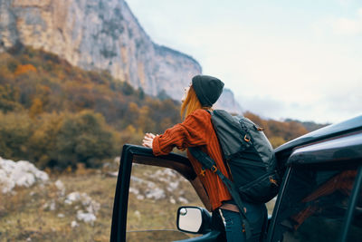 Rear view of man sitting on car against mountain