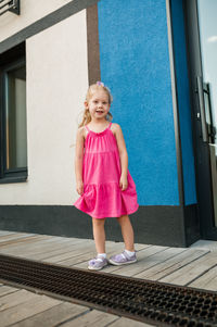 Portrait of young woman standing against building