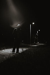 Rear view of person walking on illuminated street at night