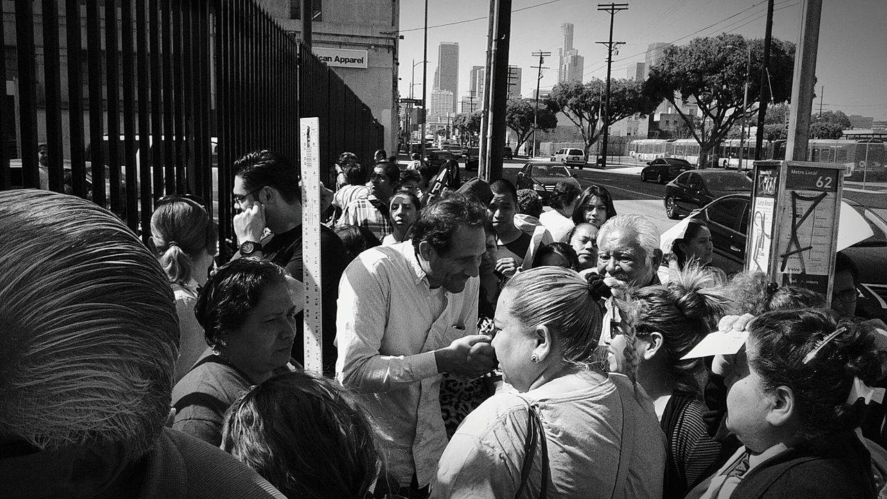 large group of people, men, lifestyles, person, leisure activity, street, crowd, sitting, casual clothing, city life, building exterior, city, togetherness, market, rear view, built structure, outdoors, day, walking