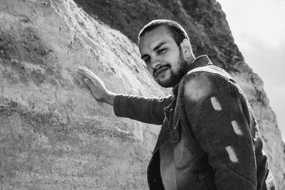 Side view of young man standing against wall