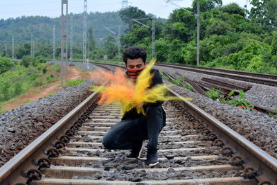 Man splashing powder paint while crouching on railroad track