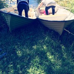 Low section of man sitting on boat moored in grass