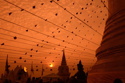 Low angle view of decorations at temple against orange sky during sunset