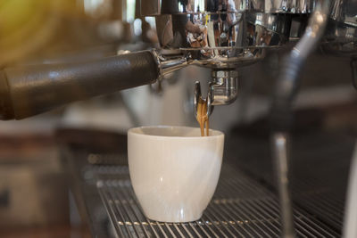 Close-up of machinery pouring coffee in cup