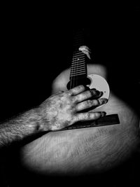 Man playing guitar against black background