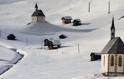 Houses on snow covered field against mountain