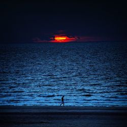 Silhouette man on beach against sky at sunset