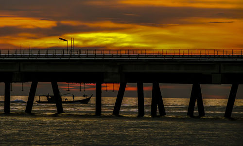 Pier over sea against orange sky
