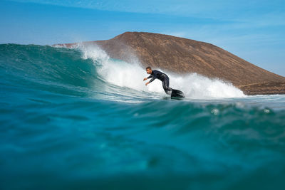 Man surfing on sea against sky