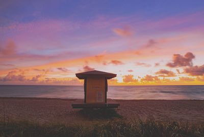 Lifeguard hut on beach against sky during sunset