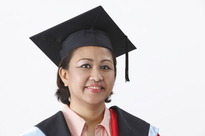 Woman in graduation gown against white background