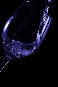 Close-up of glass over water against black background