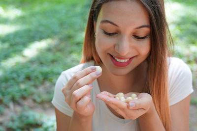 Beautiful young woman picking macadamia nuts outdoor. looks at macadamia nuts in her hand.