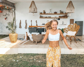 Portrait of smiling young woman standing against wall