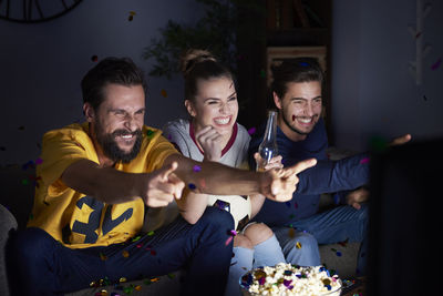 Excited friends sitting on the sofa watching tv