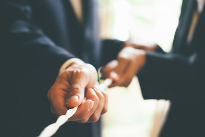 Midsection of business colleagues pulling rope at office