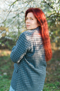 Portrait of young woman standing against trees