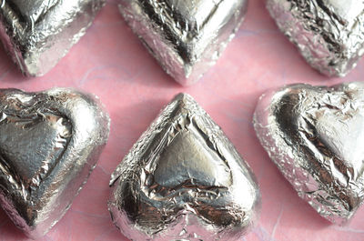 Silver foil wrapped chocolate heart shape candy on pink paper
