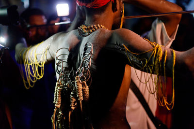 Rear view of shirtless man with hooks pierced on his back at night