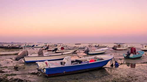 Boats moored on beach against sky during sunset