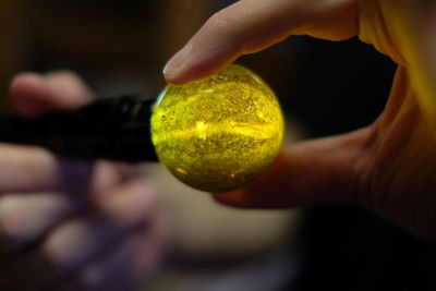 Cropped hands holding illuminated flashlight on marble