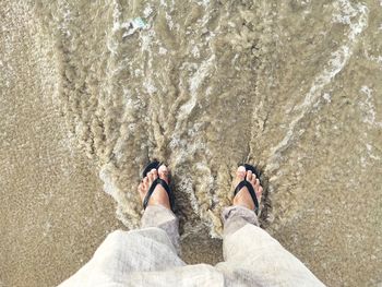 Low section of man standing on beach