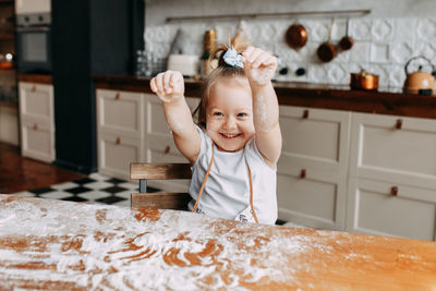 Funny emotional little girl child cooks and has fun alone in the kitchen at home