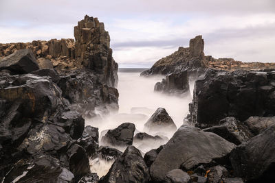 Scenic view of rocks in sea against sky