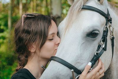 Woman kissing horse on field