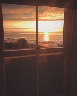 Close-up of sea seen through window during sunset