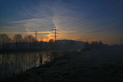 Silhouette of electricity pylon against sky during sunset