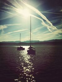 Sailboats sailing in sea against sky during sunset