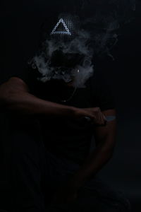 Midsection of man with smoke against black background