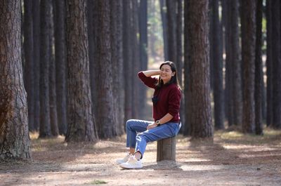 Full length of man sitting on tree trunk