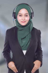 Portrait of confident businesswoman with headphones wearing hijab at call center