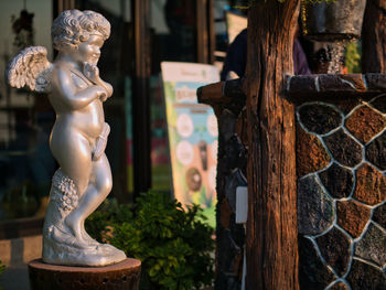 Taking photo of the boy cupid statue at park.