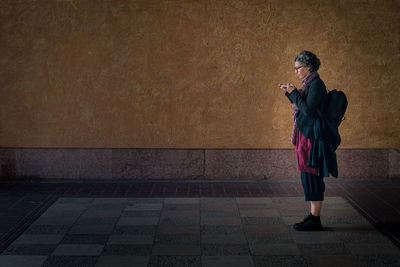 Full length of young man standing against wall