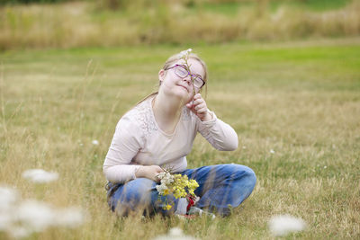 Smiling girl on meadow holding wildflowers