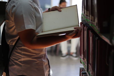 Midsection of man holding book in library