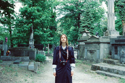 Portrait of a young woman standing against trees