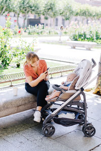 Portrait of young mother taking a walk with young baby taking a photo