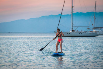 Man kayaking in sea against sky