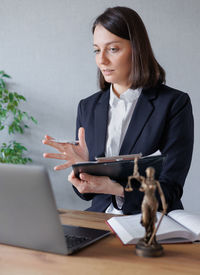 Portrait of young woman using mobile phone while sitting on table